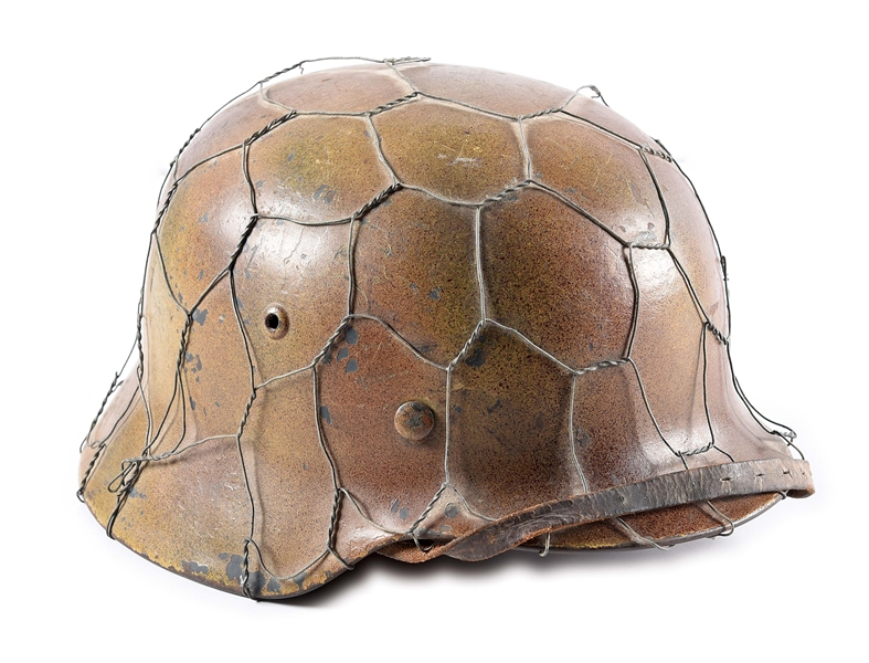 Authentic WWII German Luftwaffe M35 tri-color spray ‘chicken wire’ camouflage helmet known to collectors as a ‘Normandy’ style. Marked ‘ET68’ for the maker Eisenhuttenwerk/Herz. Luftwaffe eagle and national colors decals visible beneath camo paint. Vetted by Willi Zahn. Estimate $6,000-$8,000