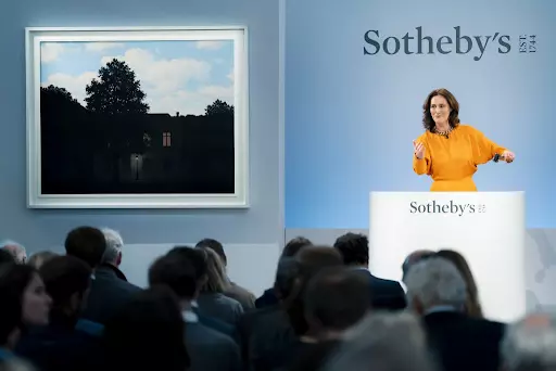 Sotheby’s Europe chairman Helena Newman with René Magritte’s L’empire des lumières (1961). Image courtesy of Sotheby’s.