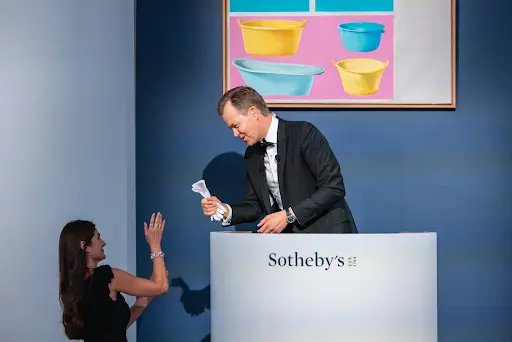 Brooke Lampley, Chairman & Worldwide Head of Sales for Global Fine Art, hands Oliver Barker the white gloves traditionally given to an auctioneer after an event where every lot sells. Photography by Julian Cassady for Sotheby’s.