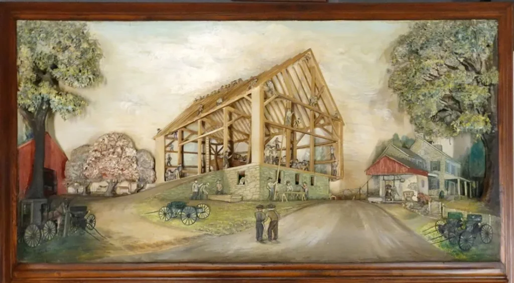Abner K. Zook (Lancaster, Pa; 1921-2003), three-dimensional carved painting depicting an Amish barn-raising. Size: 49¾ in x 25¼ in (sight), framed size 57in x 33¾in. Accompanied by lengthy personal letter sent by Zook in 1967 to the person commissioning the painting, explaining aspects of the scene in minute detail. Estimate $10,000-$15,000