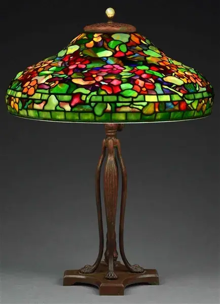 Exquisite signed/numbered Tiffany Studios Nasturtium table lamp with 19in (dia.) leaded-glass shade featuring multicolored confetti glass tiles and flowers in various shades of red, orange, purple and yellow against a green ground. Tiffany-stamped telescoping cat’s-paw base. Excellent condition. Estimate $120,000-$160,000