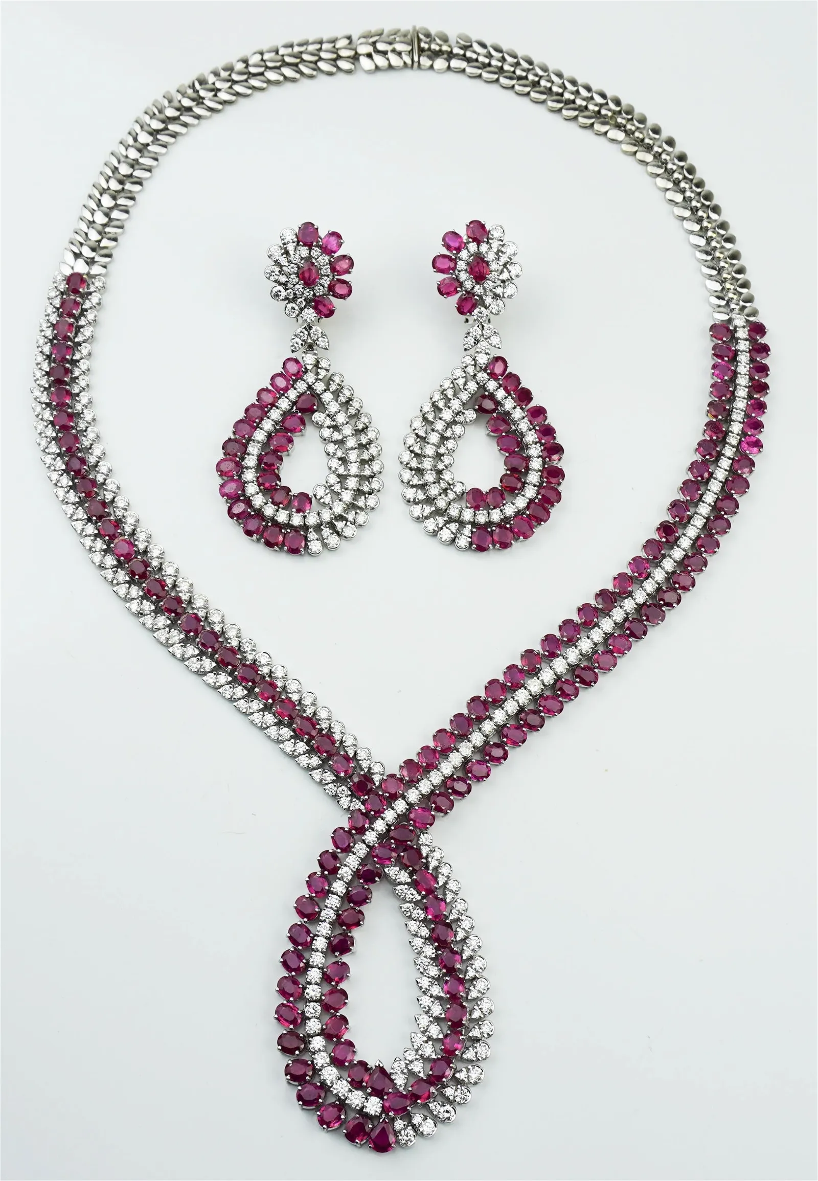 18K white gold ruby and diamond necklace and earrings suite in overlapping leaf (or petal-style) motif. Total weight of diamonds in necklace is 19.0 carats with rubies totaling 30.0 carats. Earrings: 6.46 carats of diamonds; 12.0 carats of rubies, with each earring clip having an additional pear-shape faceted ruby weighing approximately .45 carats. Suite presented in custom-fitted box. Estimate: $13,000-$15,000