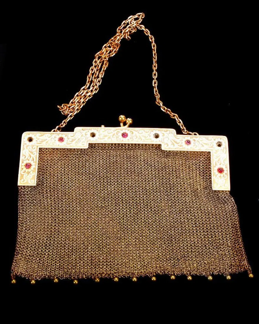 An Antique Ruby and 14k Gold Mesh Purse. The hand engraved frame set front and back with six cabochon rubies, measuring approximately 4.00mm, with unique locking mechanism, to a mesh purse and link chain handle; inner frame with later added loop (for hanging coin purse) and personalized: M.C. Chambers; weighing approximately 189.80 grams; purse measures 6 x 4 1/2 in., chain measures 20 in. (void 4 stones, minor bend on reverse side of frame). Estimate $5,000-$7,000. 
