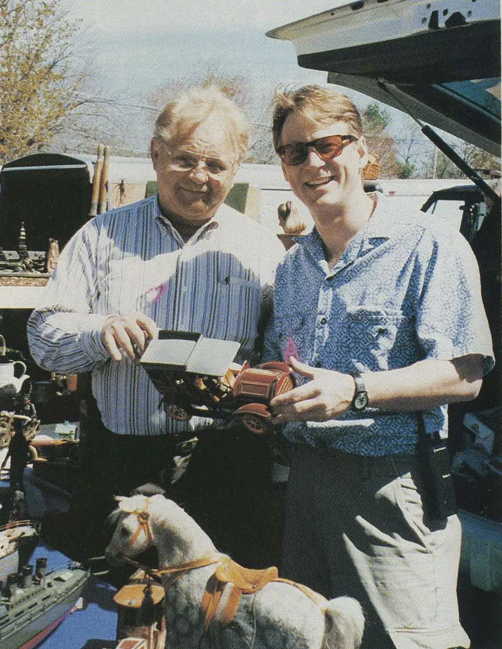 Tom Sage Sr. and his son, Tom Sage Jr., appeared together on the cover of the August 1995 issue of Antique Toy World magazine. They are shown examining an early-20th-century German tin toy car at an outdoor antique show. Image courtesy of Antique Toy World and the Sage family
